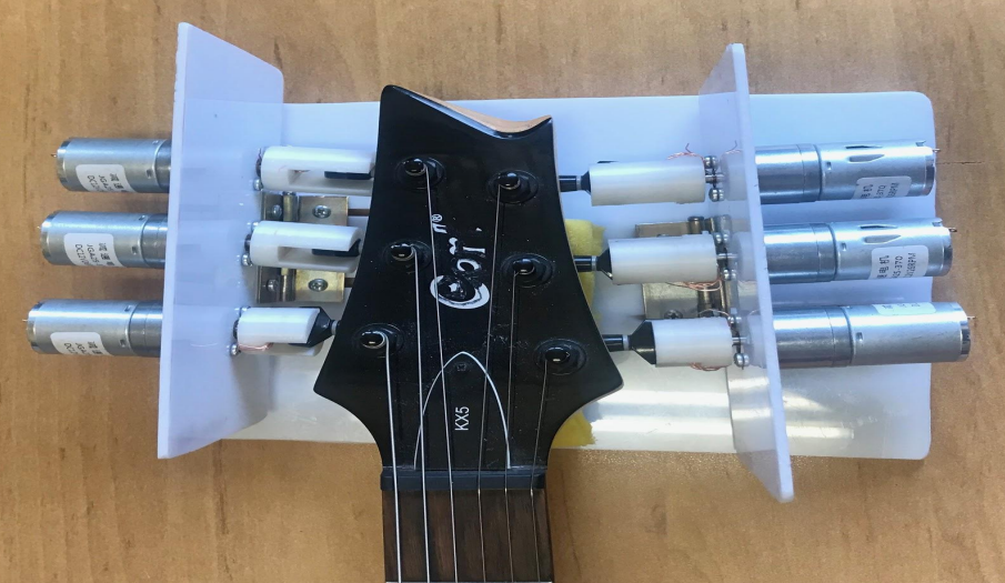 Mechanical assembly connecting DC motors to guitar tuning pegs.